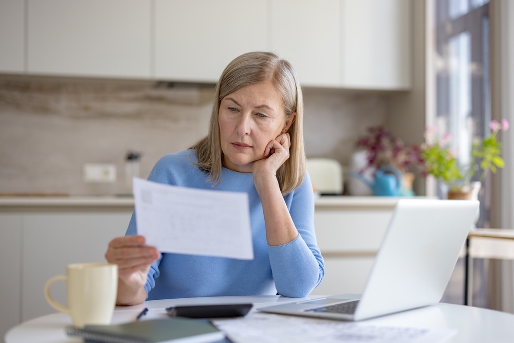 Mujer revisando documentos y gastos en casa durante una auditoría financiera personal.
