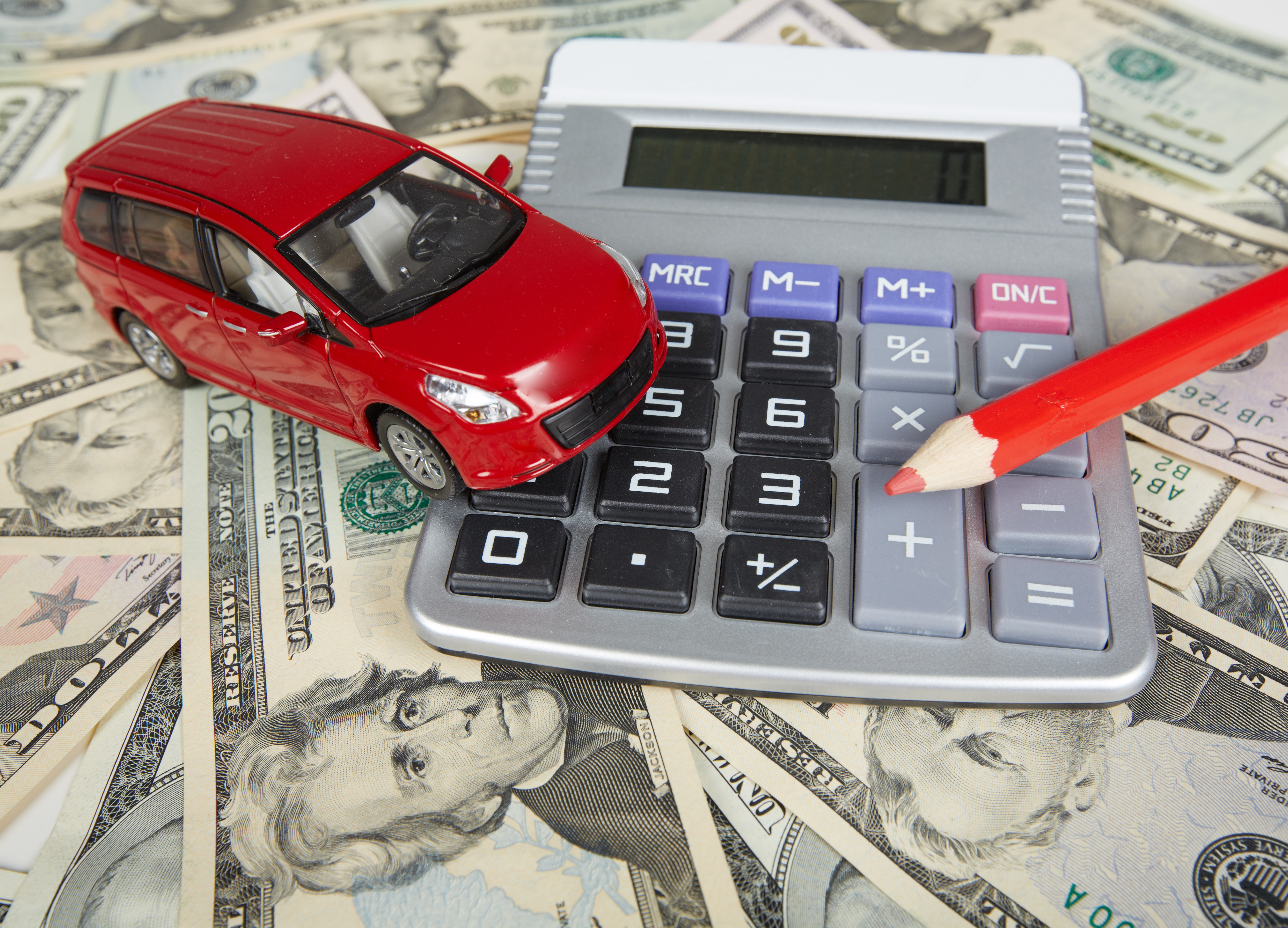auto_de_juguete_calculadora_y_lapiz_sobre_mesa_con_dolares