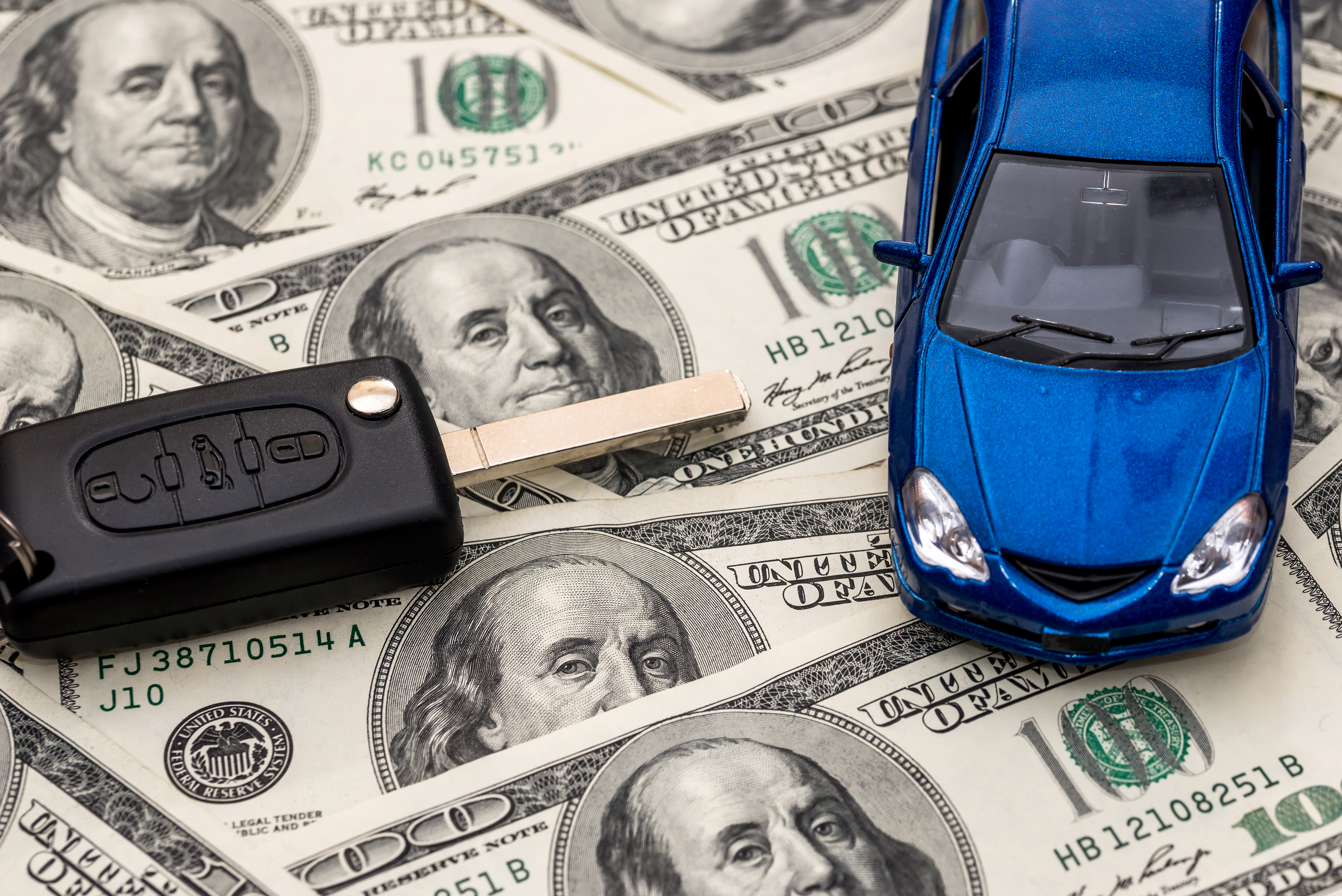 auto_azul_y_llaves_sobre_billetes_cien_dolares