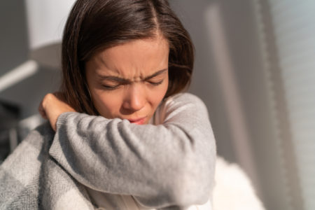 mujer estornudando en el interior de su codo para evitar coronavirus