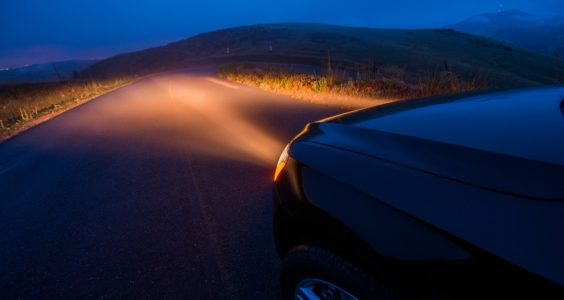 auto con los faros encendidos en carretera de noche 