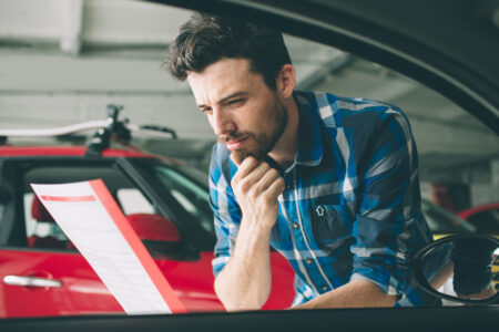 hombre joven revisando el historial del auto usado que va a comprar