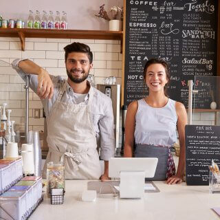 Hombre joven junto a chica en una tienda de café frente a la caja registradora
