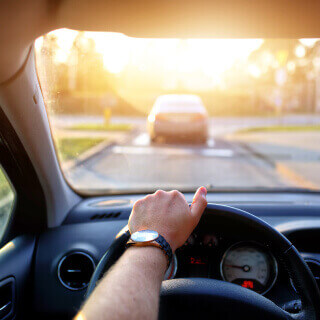 Vista frontal del interior de un auto con un conductor al volante en carretera