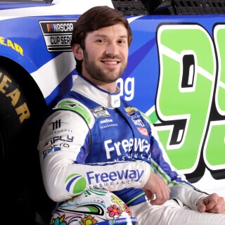 Vista frontal del ganador de las series de Nascar y Xfinity Daniel Suárez posando junto a su auto de carreras chevrolet auspiciado por Freeway