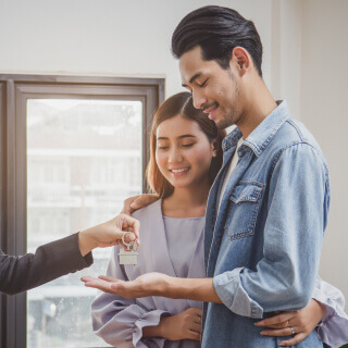 Una pareja de jóvenes recibiendo las llaves de su casa.