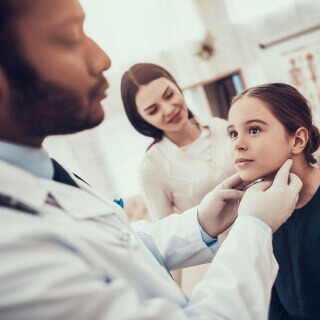 Un pediatra realizando revisión médica a una niña.
