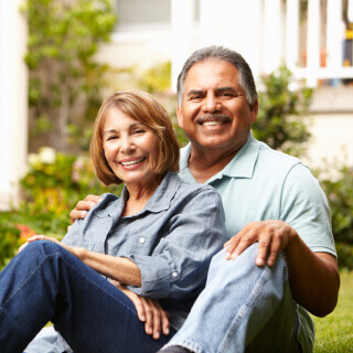 Una pareja feliz de mediana edad sentada en el patio trasero de una casa.