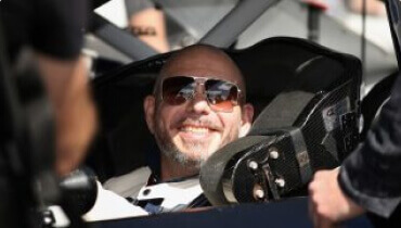 Foto improvisada del cantante y copropietario Pitbull en un auto de carreras sonriendo