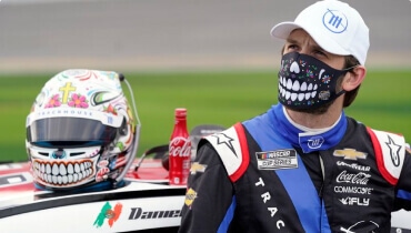 El campeón de las series NASCAR Cup y Xfinity Daniel Suárez posando con una coca cola y máscara
