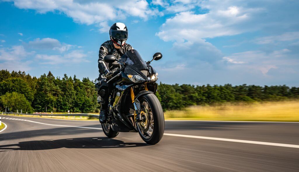 Un hombre en motocicleta en la carretera mientras tiene su cobertura de seguro de moto