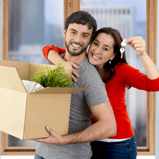 Joven pareja hispana sonriendo por su nuevo departamento con cobertura de seguro de propietarios