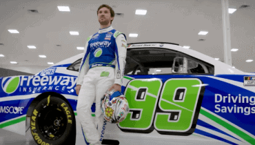 Daniel Suarez con su casco posando delante de su auto NASCAR patrocinado por Freeway Seguros