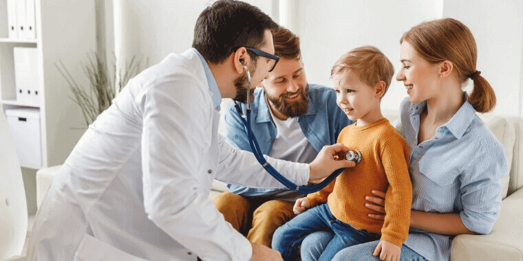 Doctor revisando latidos de corazón de niño mientras su familia lo conforta