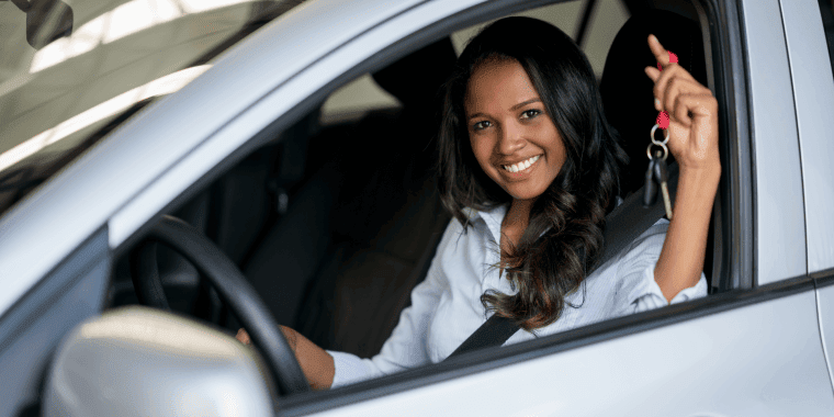 Mujer feliz sosteniendo las llaves de su nuevo coche en el concesionario