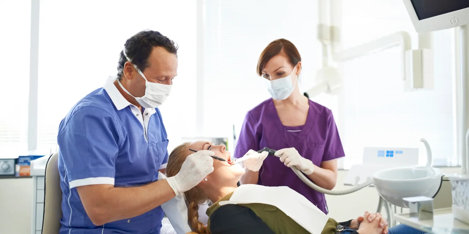 Odontólogo y asistente atendiendo a paciente en su consultorio