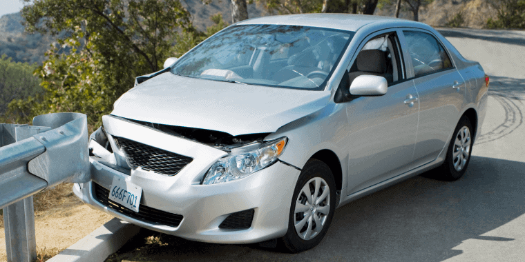 Coche empotrado en barrera de carretera.