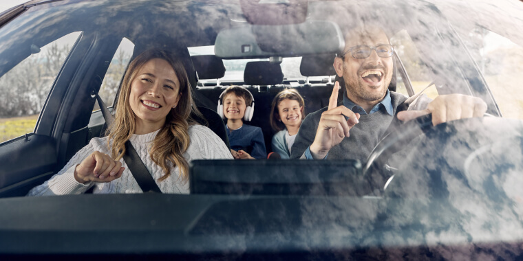 Familia feliz cantando dentro de auto en movimiento