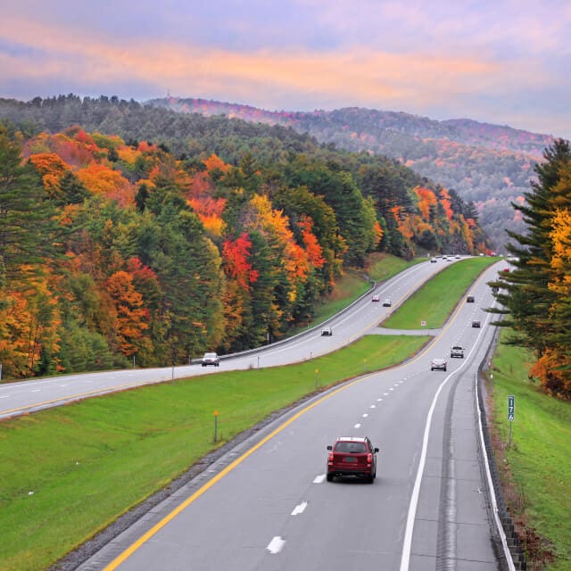 Autopista de ida y vuelta en Vermont durante el otoño con vehículos en la vía