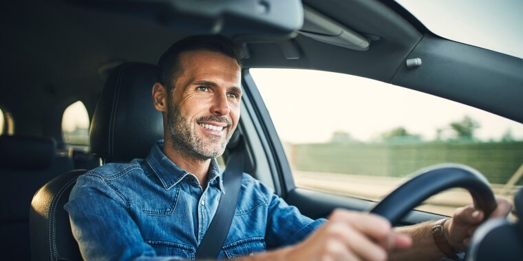 Hombre de 60 años agarrando un volante de auto con mirada perspicaz