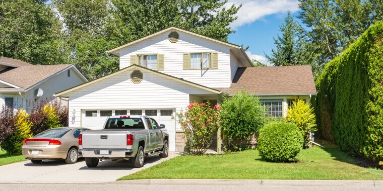 Casa con dos carros con seguro en la entrada.