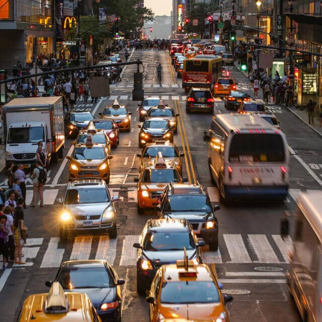 Tráfico en calle de New York con autos, taxis y autobuses en ambas direcciones