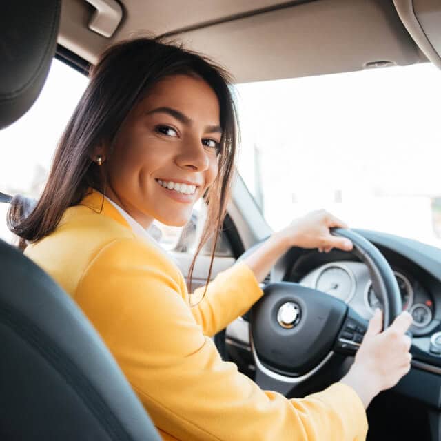 Mujer sonriente conduciendo un auto