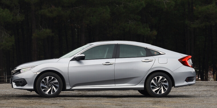 Honda Civic de perfil sobre una plataforma y de fondo un bosque