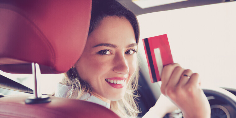 Mujer dentro de un auto con una tarjeta para hacer AutoPay