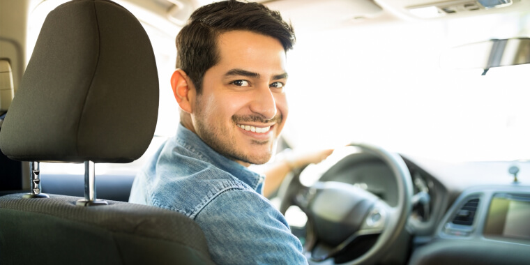 Hombre sonriendo en el asiento de su auto