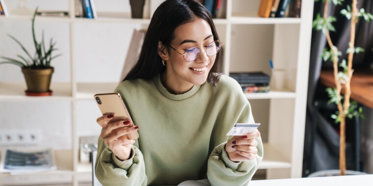 Mujer joven feliz con su tarjeta de crédito Yendo