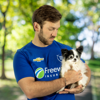 Daniel Suarez con una playera de Freeway Seguros y sosteniendo un perro.