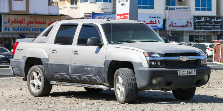 Chevrolet Avalanche gris estacionada frente a varias tiendas comerciales