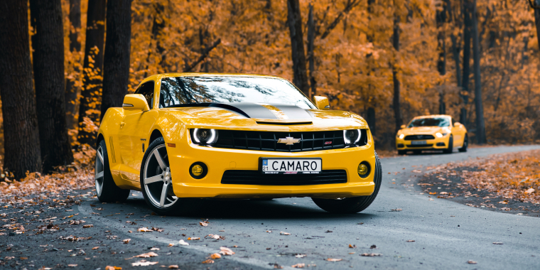 Chevrolet Camaro amarillo en medio del bosque de otoño