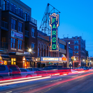 Edificios, teatro y tráfico en la ciudad de Fargo en Dakota del Norte al anochecer.