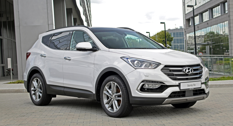 Hyundai Santa Fe blanca estacionada frente a edificios en posición diagonal