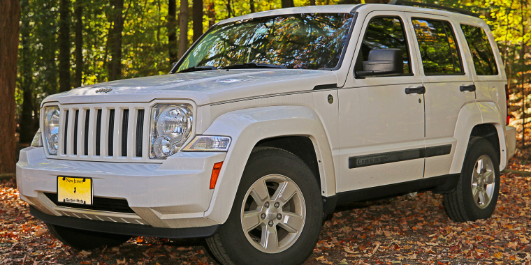 Jeep Liberty todoterreno estacionada en un verde bosque.