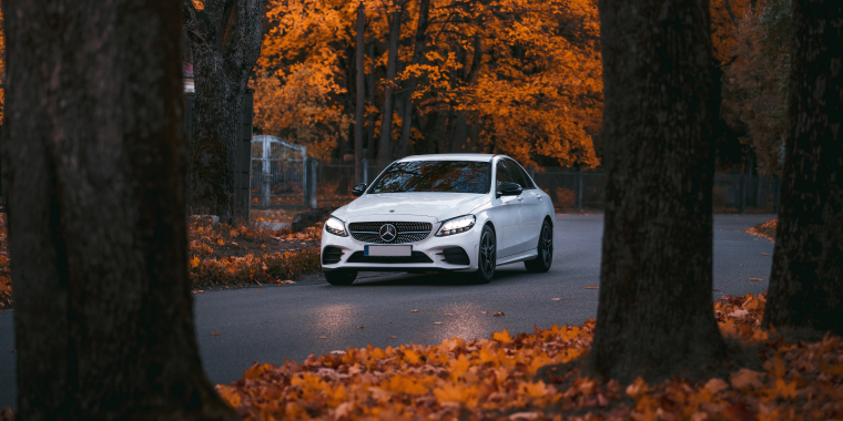 Mercedes C-Class blanco en medio de un bosque durante el otoño