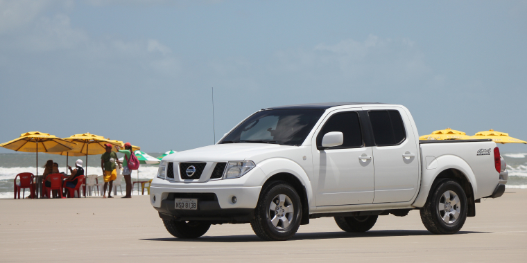 Nissan Frontier blanca fuera de la carretera estacionada frente a la playa