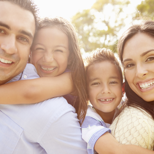 Padre, madre, hijo e hija latinos abrazados y felices.