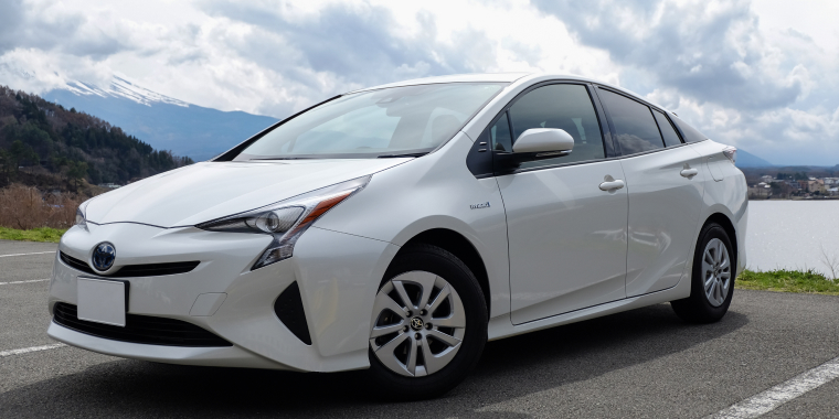 Toyota Prius plateado en medio de la naturaleza, frente a un río y montañas