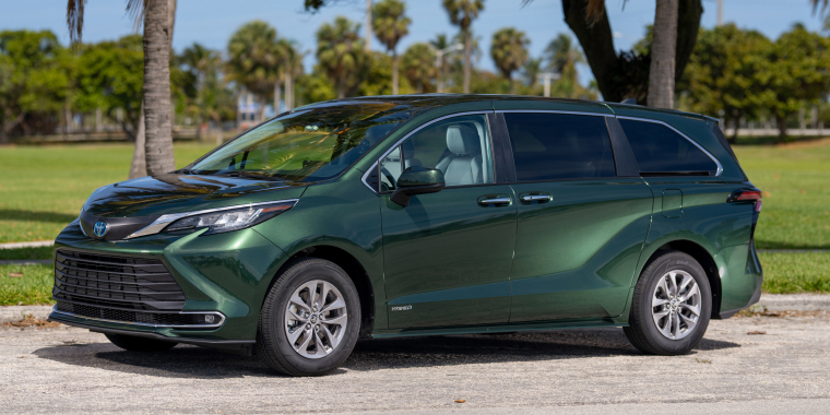 Toyota Sienna verde parqueada frente a un par de palmeras en un parque