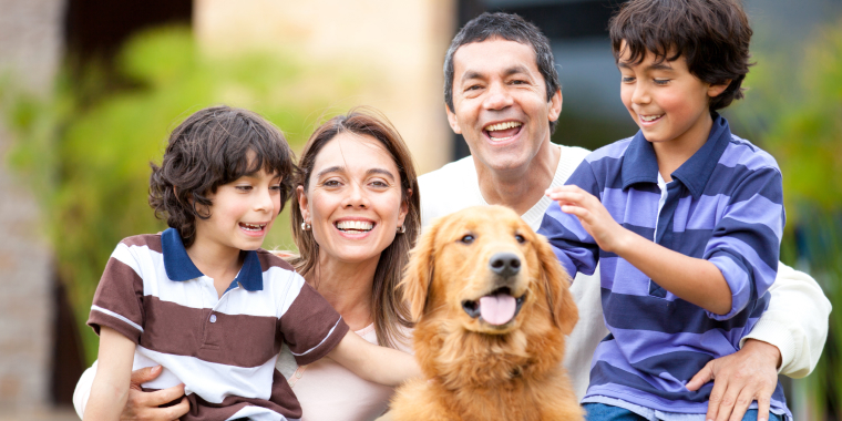 Familia hispana sonriendo y jugando con su perro
