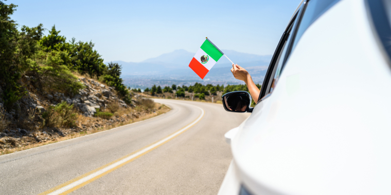 Mujer agitando una bandera mexicana mientras está protegida con un seguro de auto para viajar a México barato.