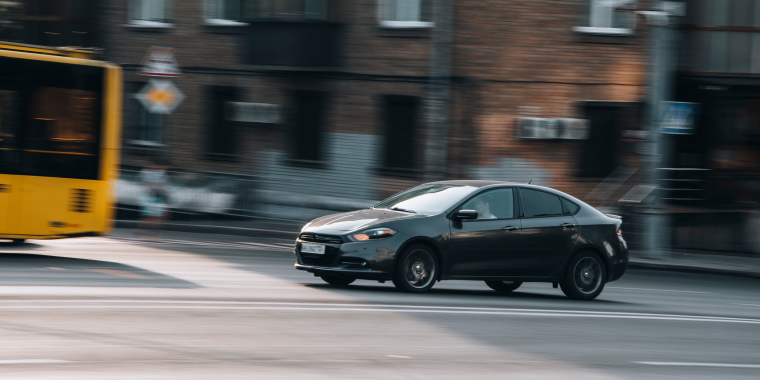 Dodge Dart negro avanzando en la calle de una ciudad a gran velocidad