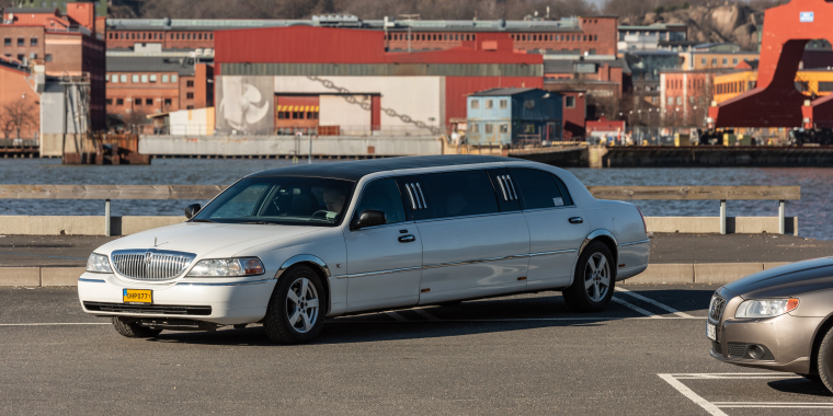 Lincoln Town Car blanca dando vuelta frente a un río.