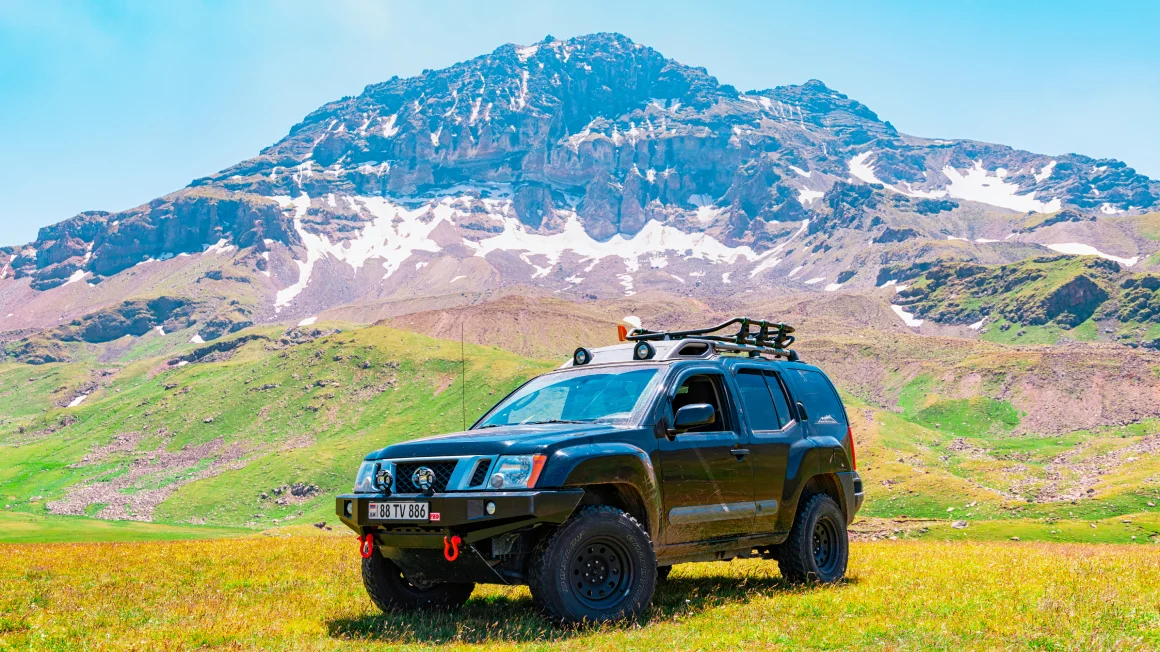 Nissan XTerra negra todoterreno estacionada debajo de las montañas 