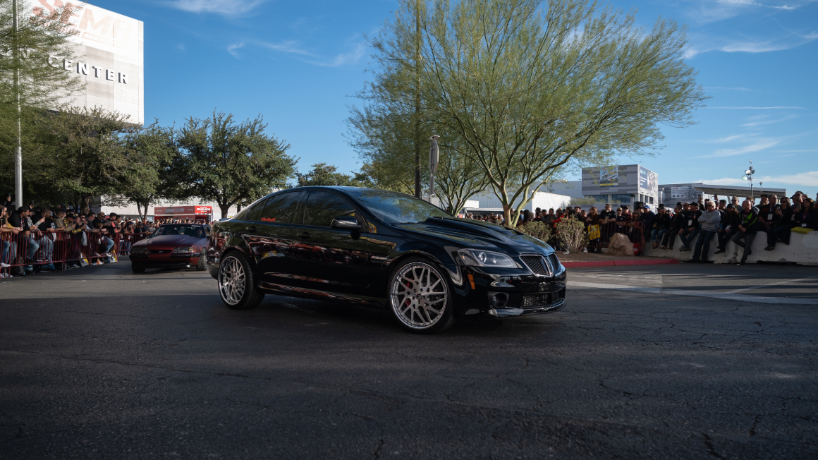 Pontiac G6 color negro avanzando en la calle en un evento de demostración de autos. 