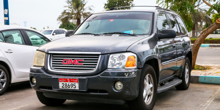 GMC Envoy negra estacionada frente a unas palmeras