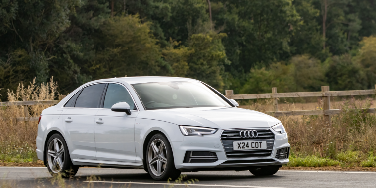 Audi A4 avanzando en una carretera con muchos árboles durante el día. 